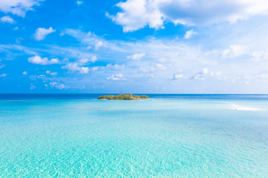 Island In The Middle Of The Sea Under Blue Sky And White Clouds