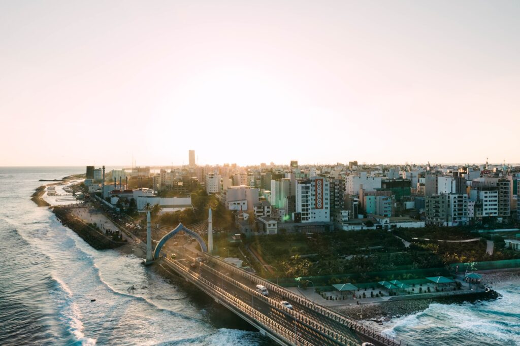 Modern Sinamale bridge with gates located near sea with waving sea and residential buildings in coastal town against cloudless sky